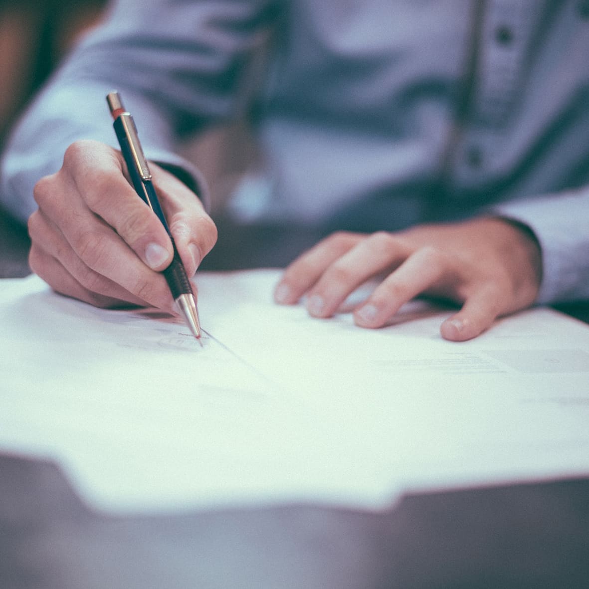 Hand die met een pen een contract ondertekent op een bureau