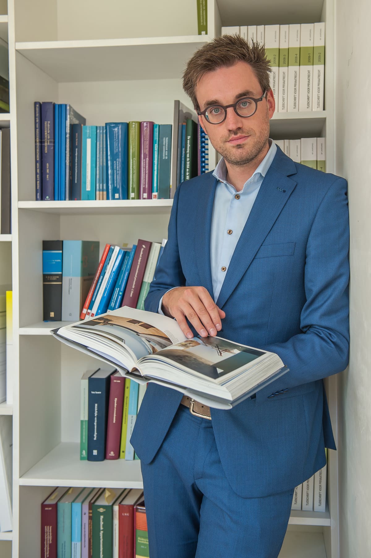 Laurent Samyn, advocaat bij Melis Advocaten, met een naslagwerk voor de bibliotheekkast van het kantoor